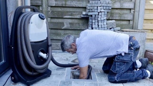 Loodgieter ontstopt buitenriool met professioneel gereedschap